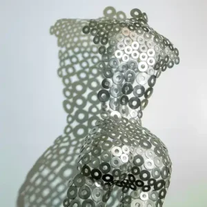 Main product photo of a handcrafted female torso sculpture made of stainless steel washers, casting a dramatic geometric shadow on a white background.